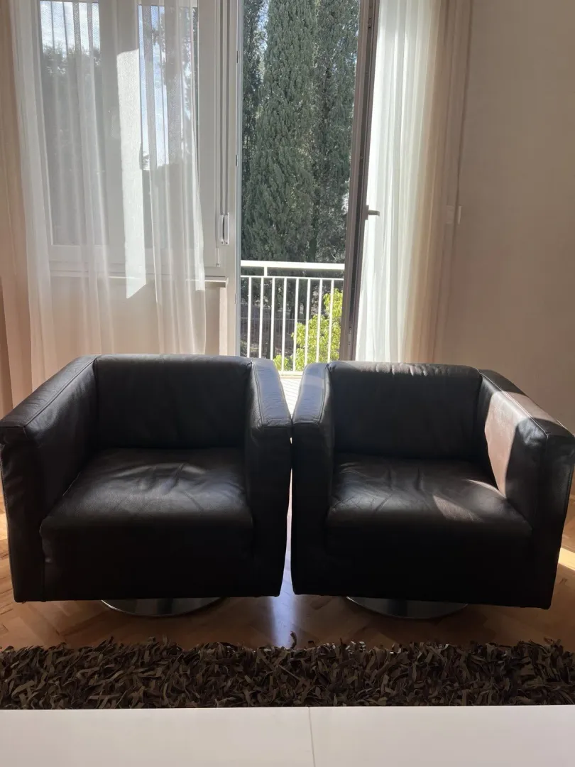 Two leather armchairs positioned in front of a balcony door.