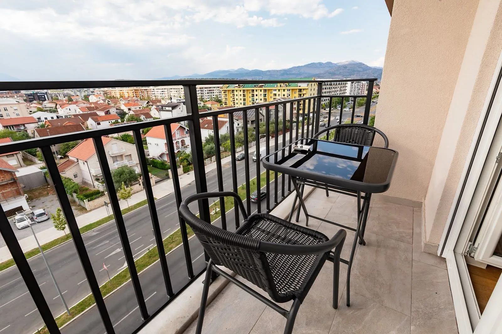 Furnished balcony with seating set and city view.