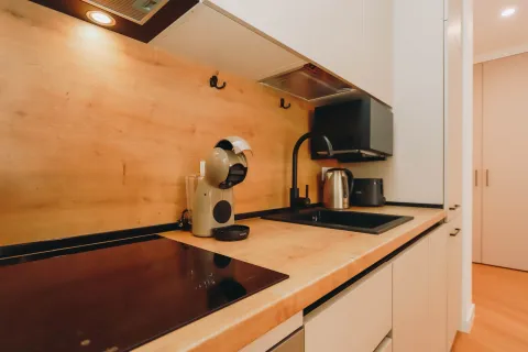 Modern kitchen with wooden elements, built-in cooktop, and sink. - image 4