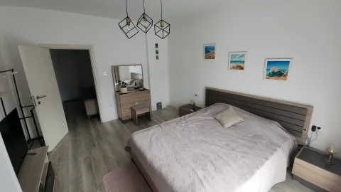 Prostrana spavaća soba sa bračnim krevetom, komodom i modernim lusterima. - image 4