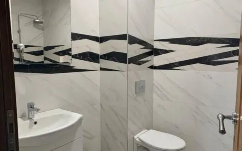 Manje kupatilo obloženo keramičkim pločicama sa umivaonikom i tuš kabinom. - image 3