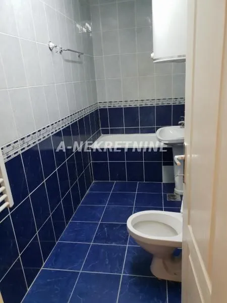 Kupatilo opremljeno sa kadom, umivaonikom i toaletom, obloženo pločicama u plavim tonovima.