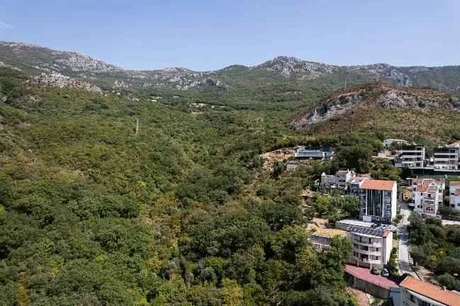 Pogled na brdoviti pejzaž sa zelenilom i okolnim objektima.