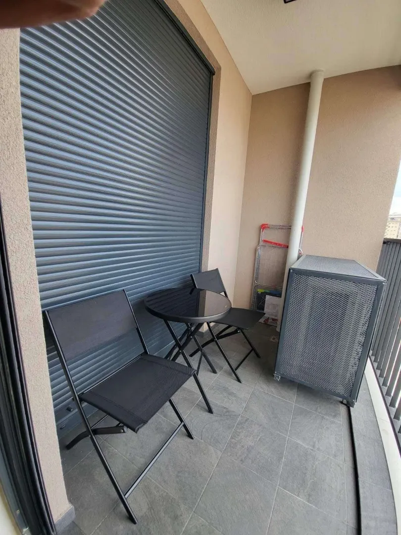 Uski balkon sa dvije sklopive stolice i malim okruglim stolom.