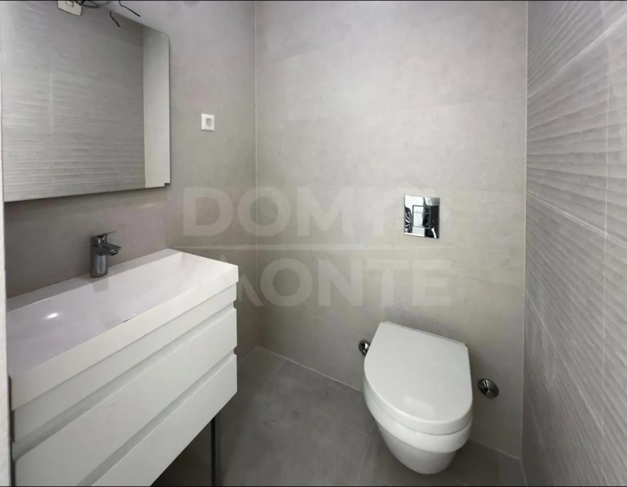Moderno opremljeno kupatilo sa umivaonikom i wc šoljom u neutralnim tonovima.