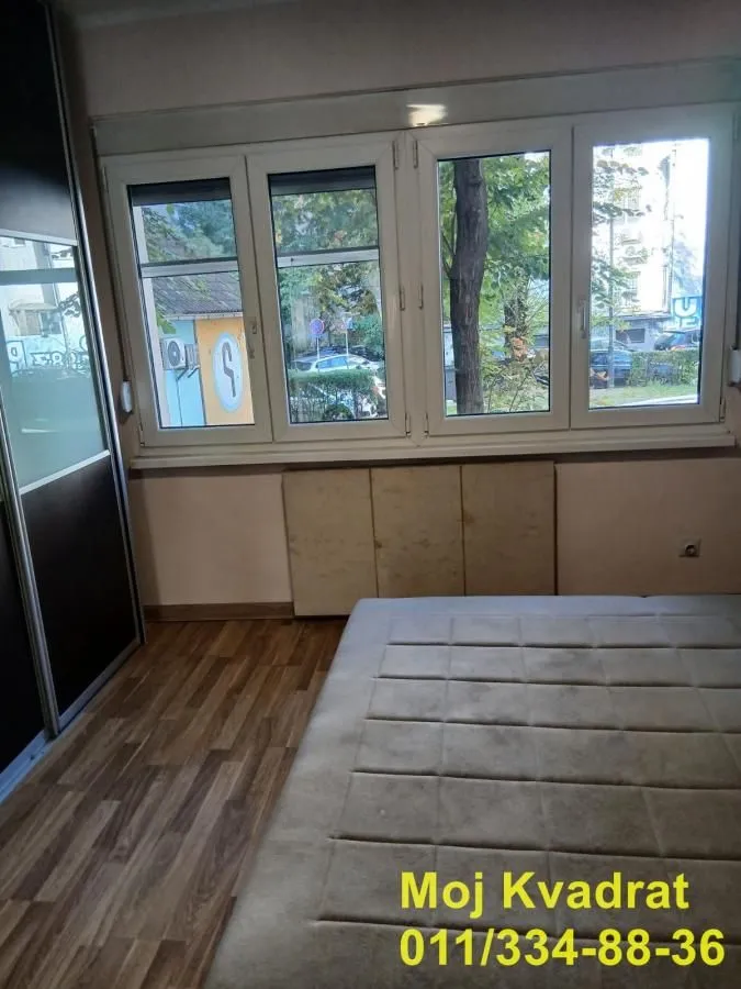 Bedroom with a large window, a bed, and a built-in wardrobe.