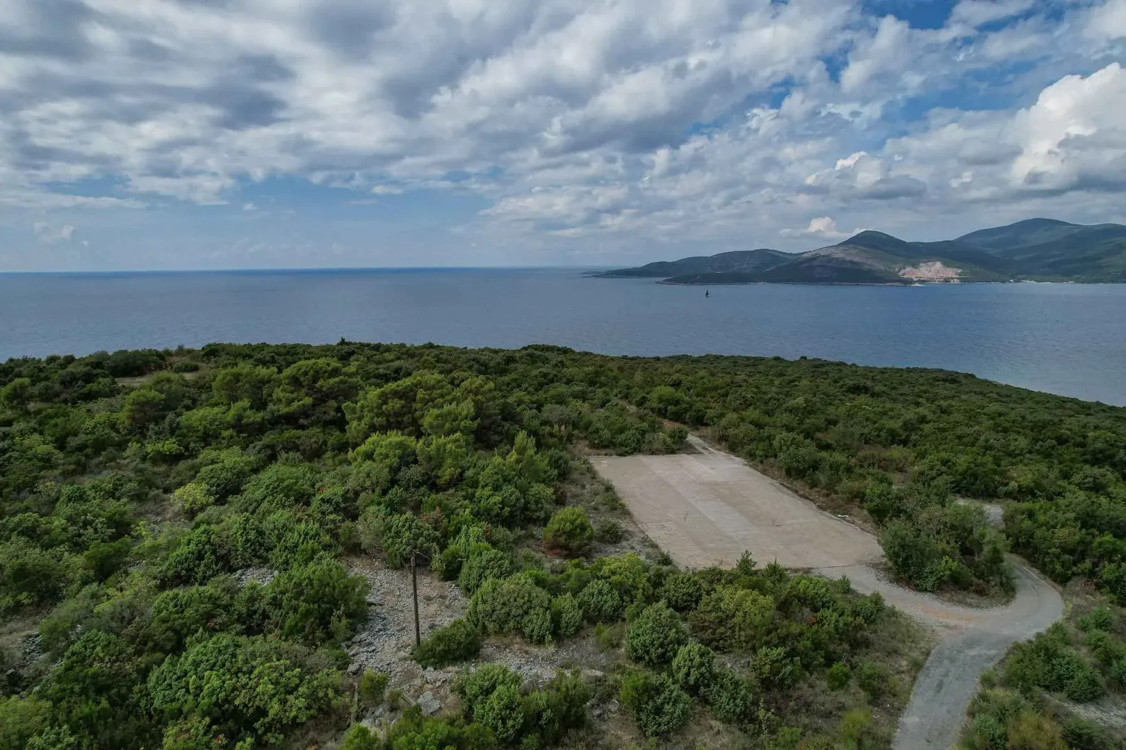 Pogled iz vazduha na šumoviti pejzaž sa otvorenim pogledom na more.