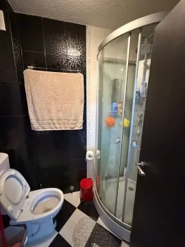 Manje kupatilo sa tuš kabinom, WC šoljom i crno-bijelim pločicama na podu. - image 10