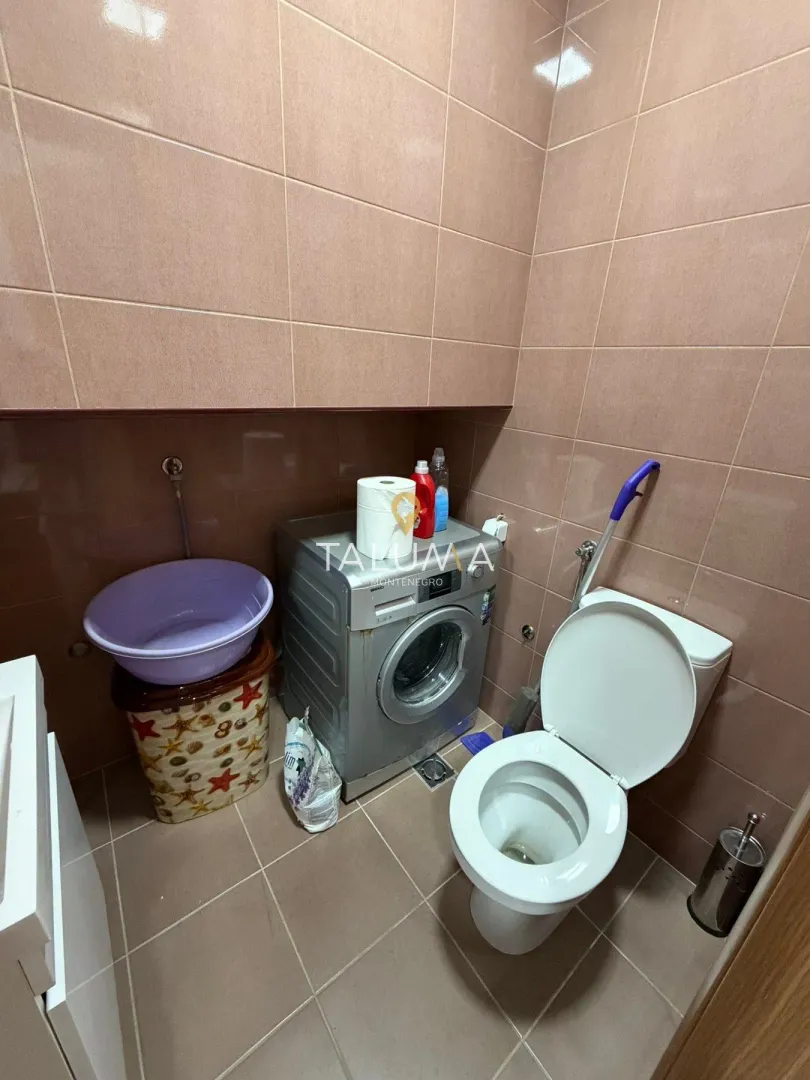 Tiled bathroom featuring a washing machine and a toilet.