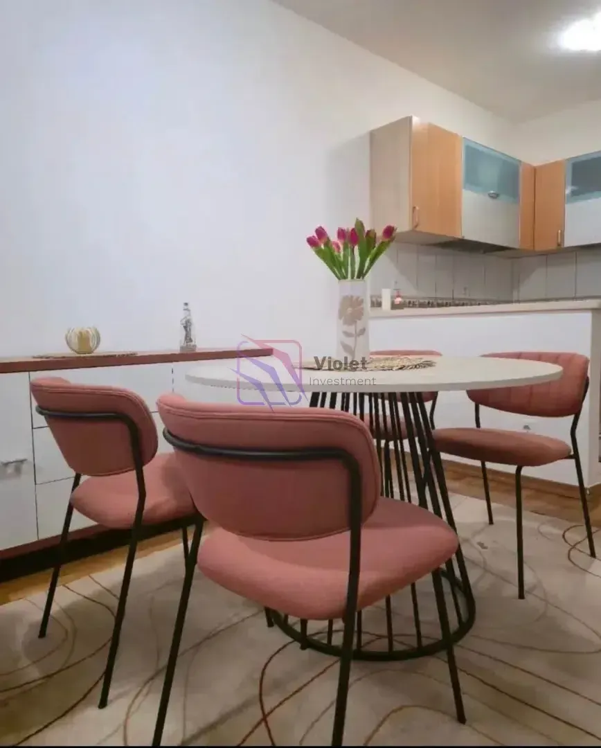 Dining table with pink chairs and a view of the kitchen.