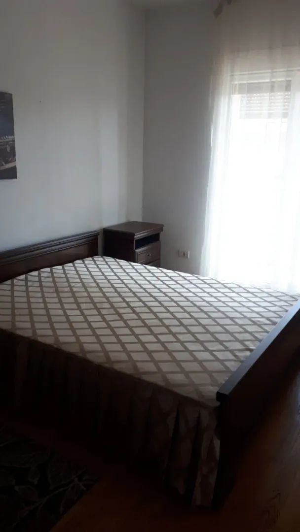 Spavaća soba sa bračnim krevetom i noćnim stočićem.