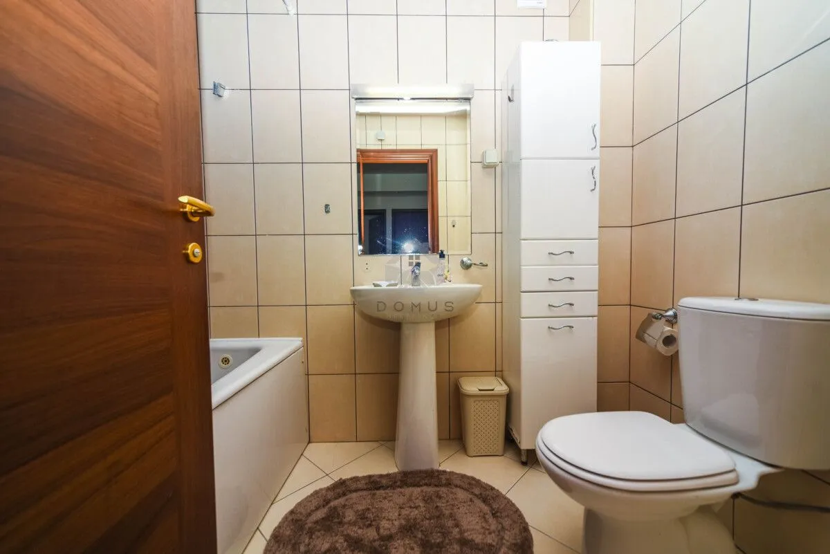 Kupatilo opremljeno umivaonikom, WC šoljom, kadom i visokim ormarićem.