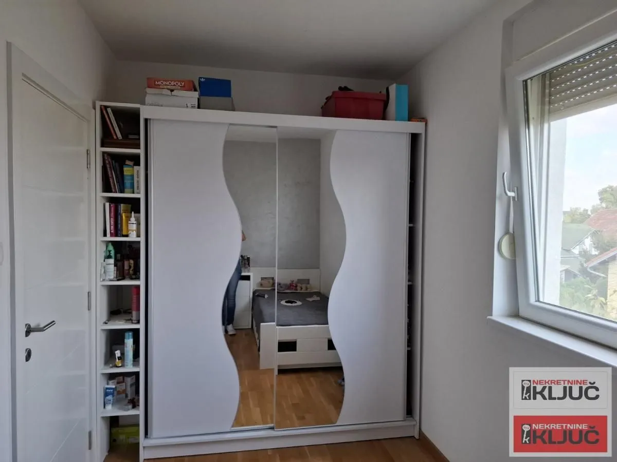 Spavaća soba sa velikim belim ormarom i krevetom.