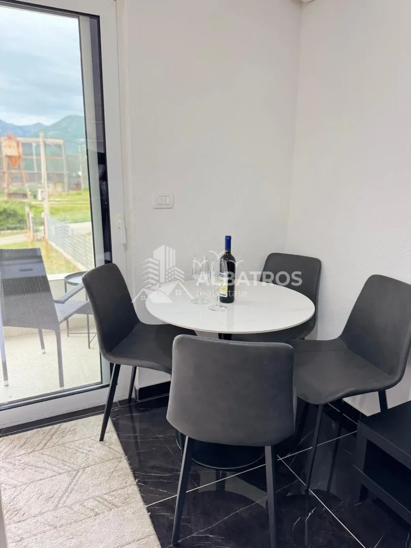 Dining corner with a round table and four chairs next to the balcony door.
