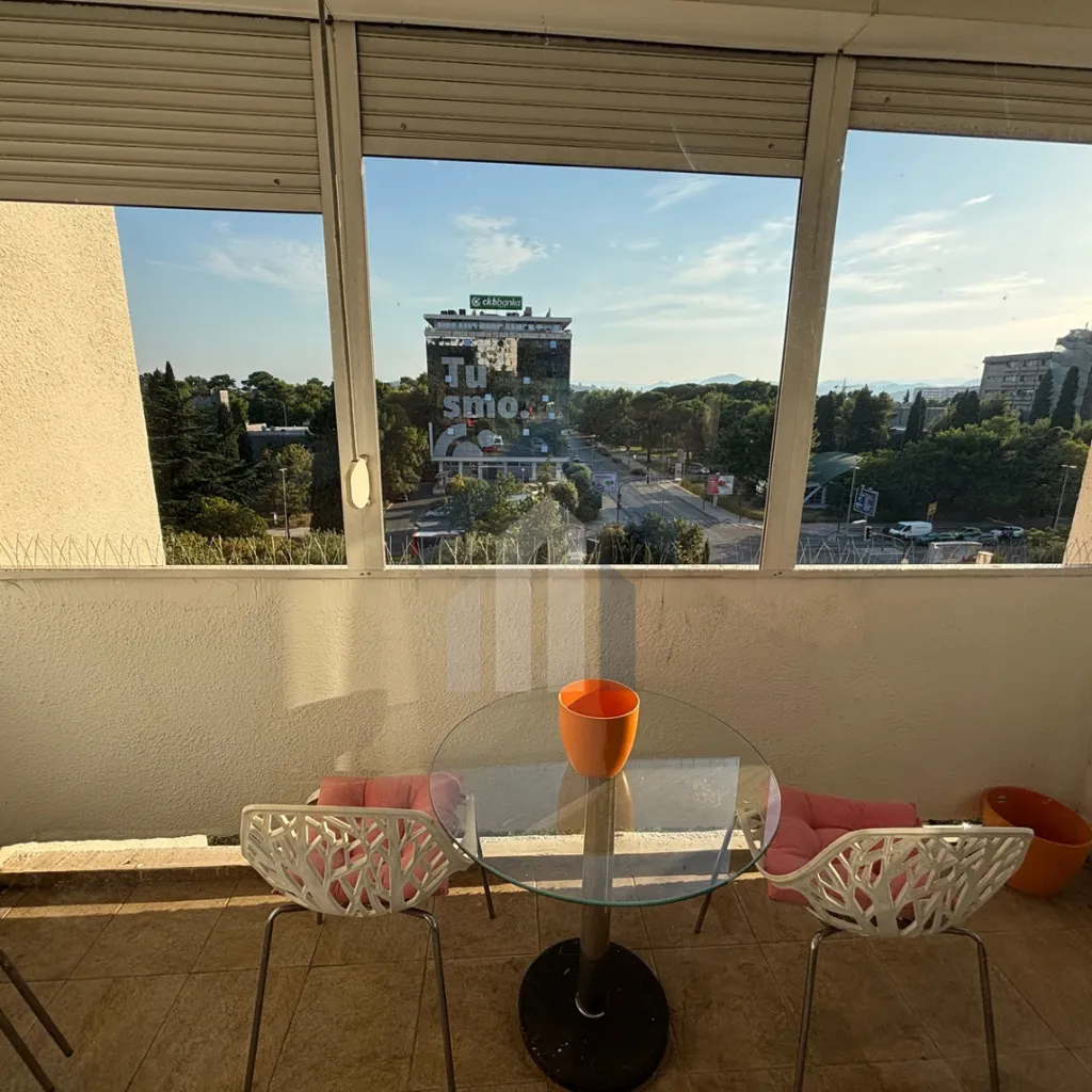 Enclosed terrace with a table, two chairs, and a city view.