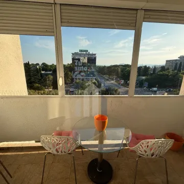 Enclosed terrace with a table, two chairs, and a city view. - image 17