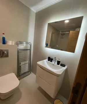 Modern bathroom equipped with a washbasin, toilet, and backlit mirror. - image 6