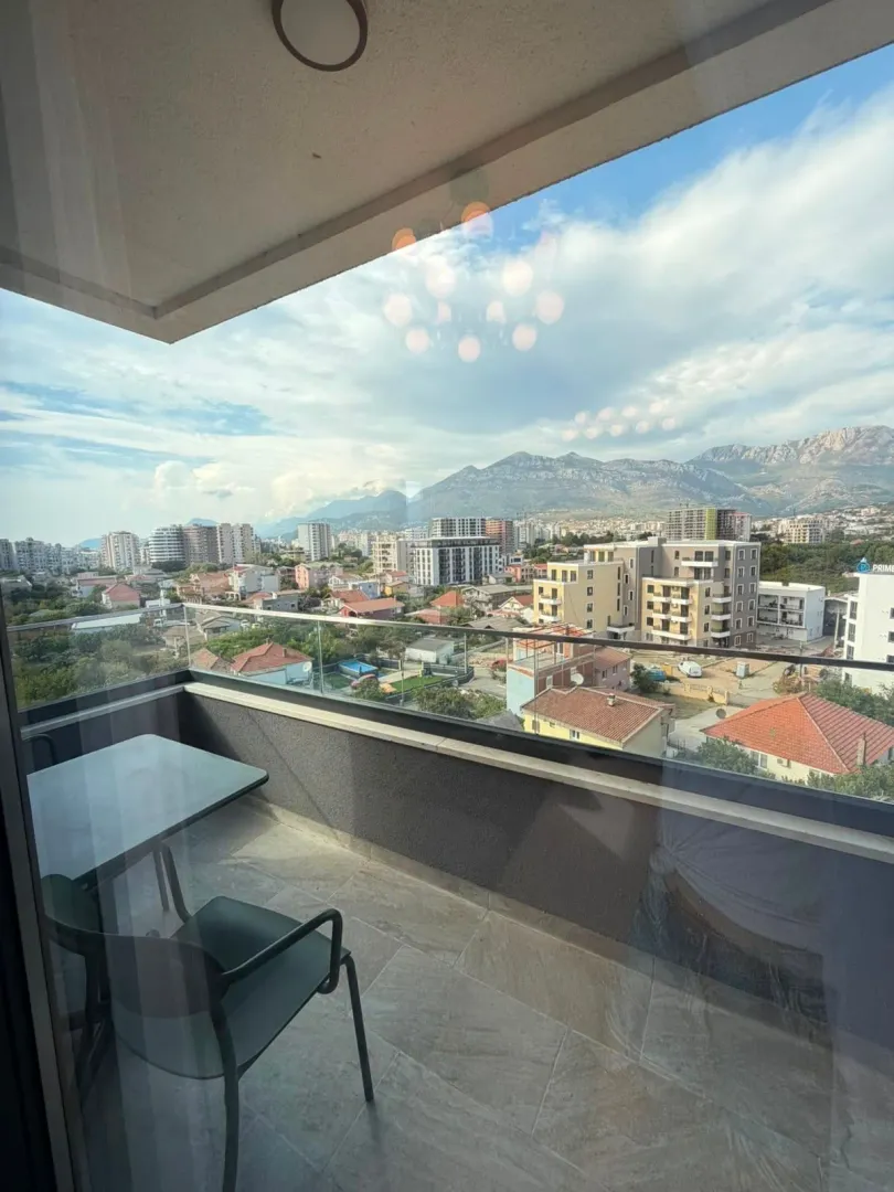 Namješten balkon sa stolom i stolicama i pogledom na grad.