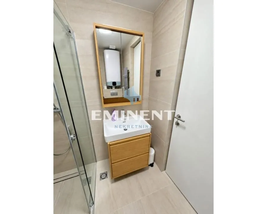 Modern bathroom equipped with a washbasin, mirror and walk-in shower.