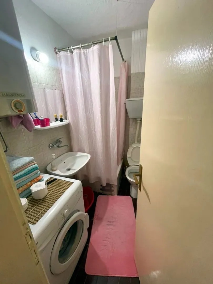 Smaller bathroom with a bathtub, washbasin, and washing machine.