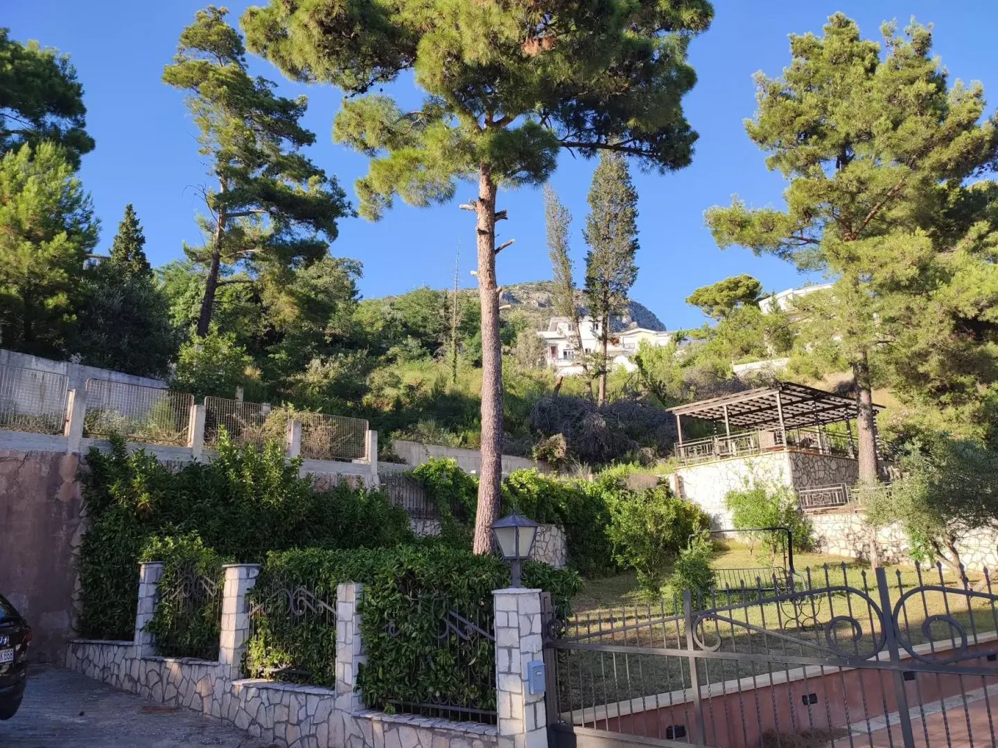 Dvorište sa ogradom i zelenilom ispred kuće.