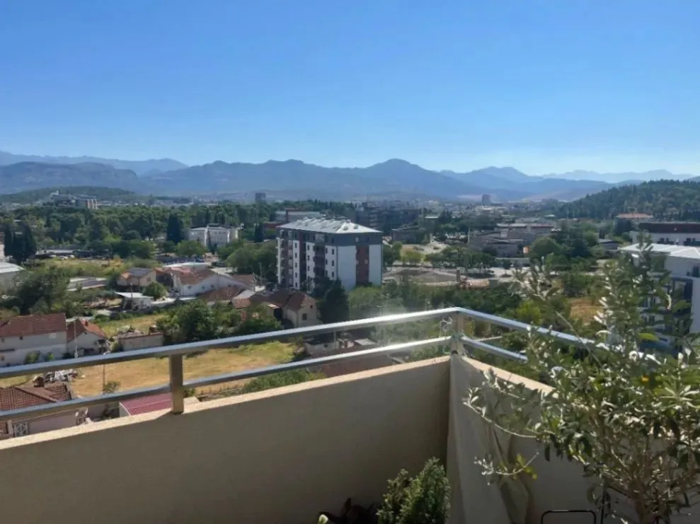 Pogled sa terase na grad i planine u pozadini.