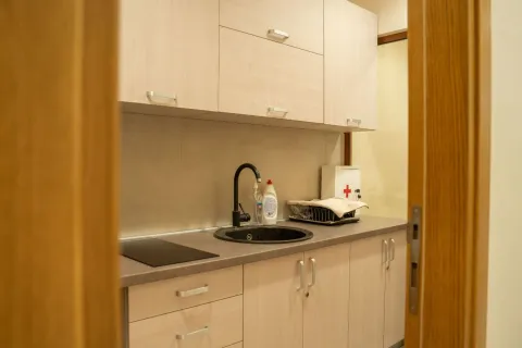 Smaller kitchen with wooden cabinets and a sink. - image 12