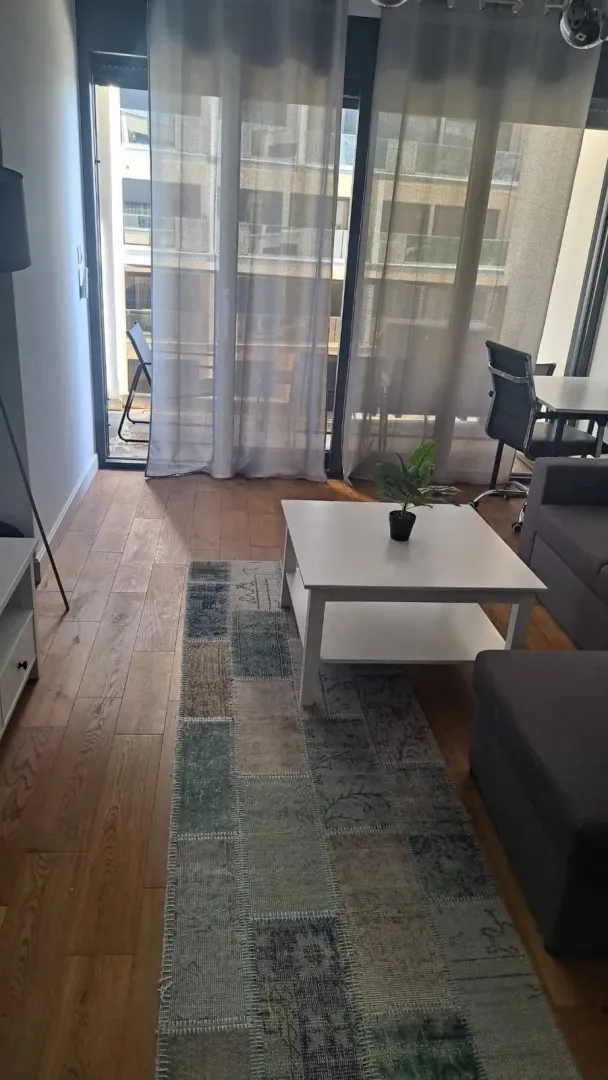 Dnevna soba sa garniturom, stočićem i izlazom na terasu.