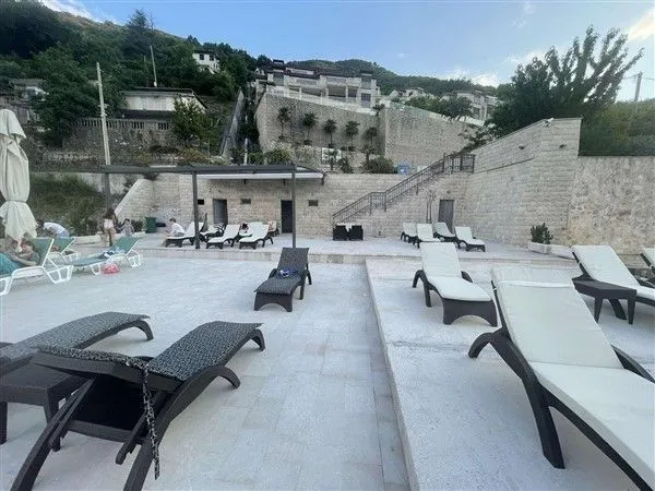 Popločana terasa sa ležaljkama ispred kamene zgrade.