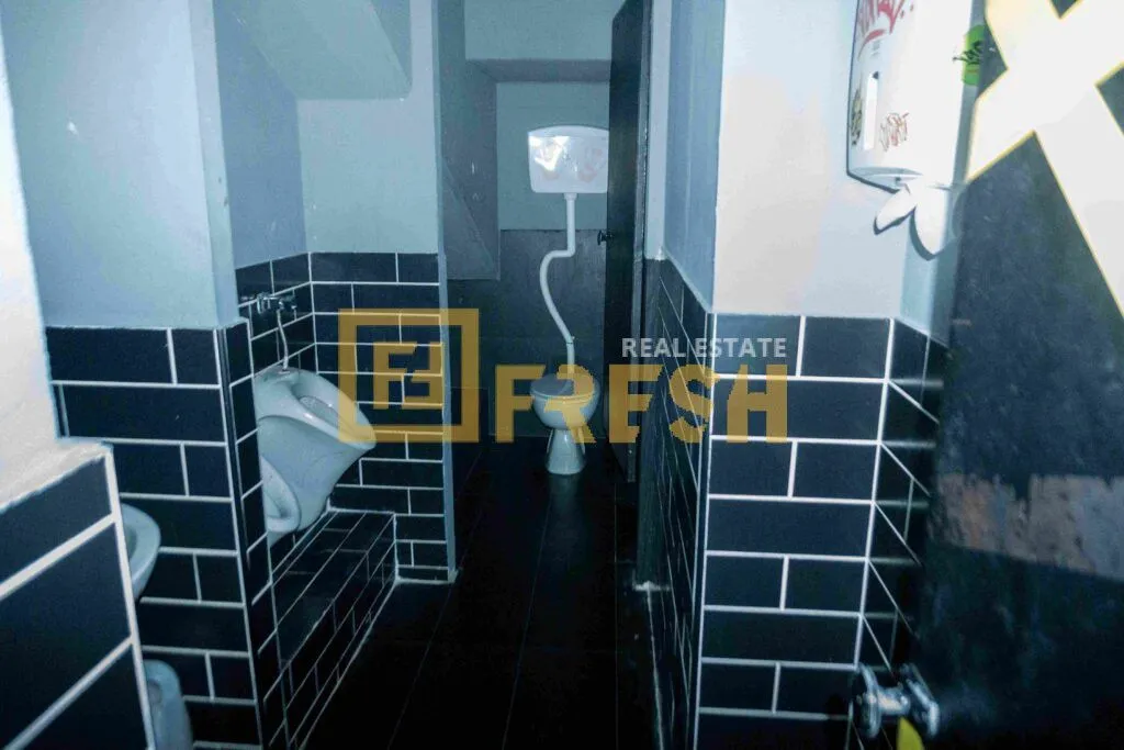 View of the bathroom with dark tiles and sanitary fixtures.