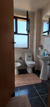 A bathroom with a window, toilet, and sink viewed through a doorway. - image 15