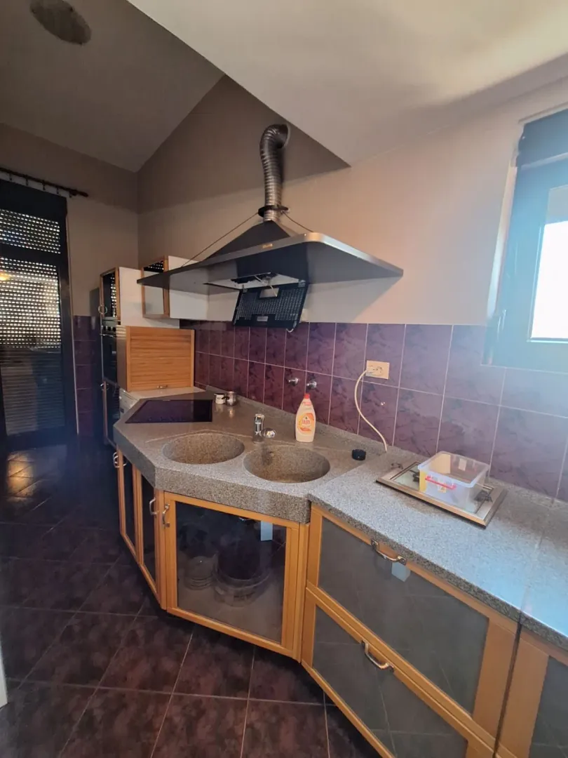 Kitchen with wooden cabinetry, a sink, and an exposed extractor pipe.