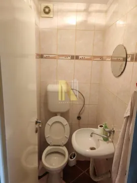 Manje kupatilo sa WC šoljom, umivaonikom i pločicama na zidovima. - image 7