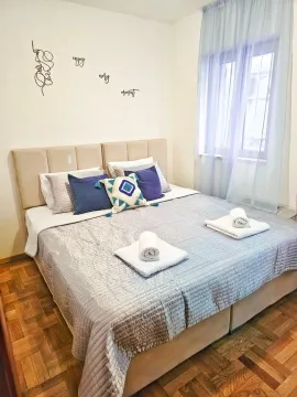 A furnished bedroom with a double bed and a window with light curtains. - image 14