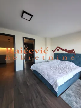 Spavaća soba sa bračnim krevetom i tamnim drvenim podom. - image 15