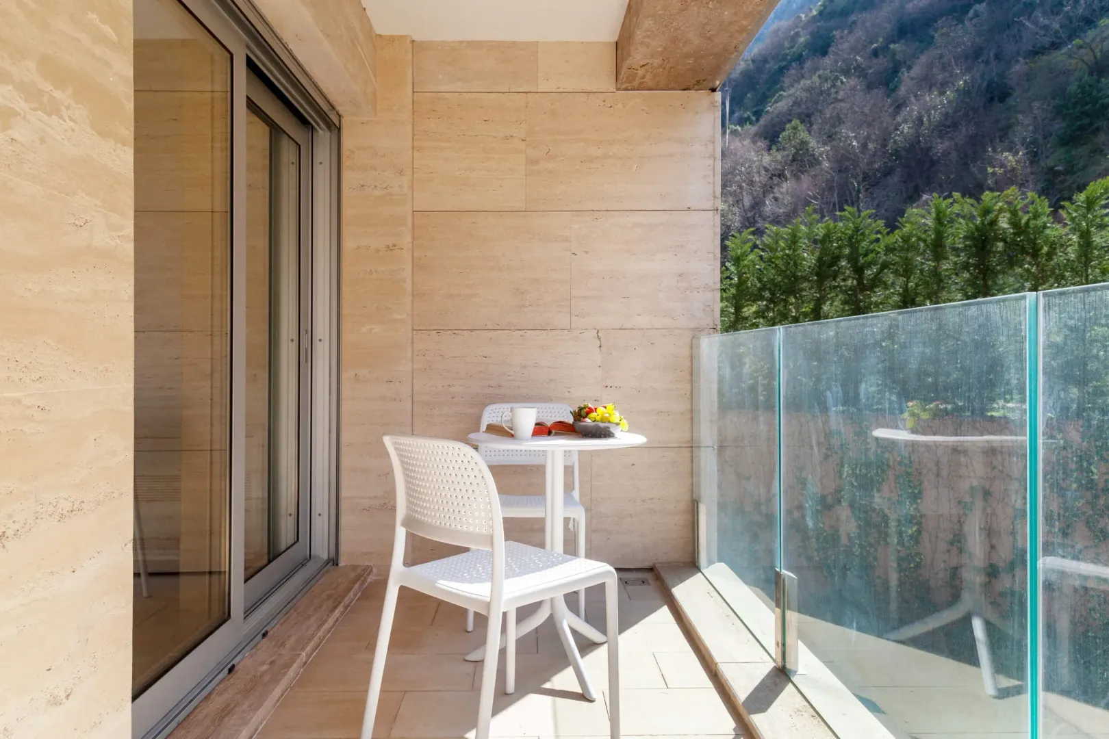 Covered terrace with a dining table, chairs, and a nature view.