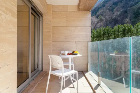 Covered terrace with a dining table, chairs, and a nature view. - image 11