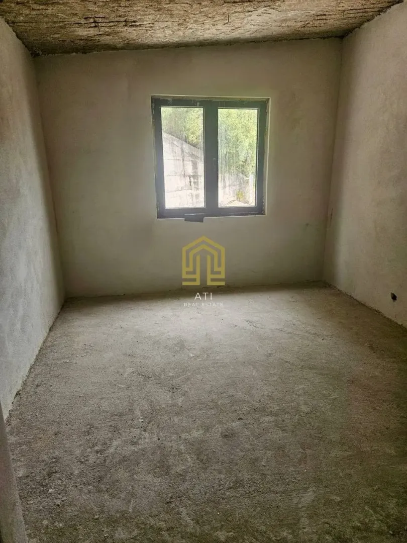 Neopremljena prostorija u sivoj fazi sa jednim prozorom.