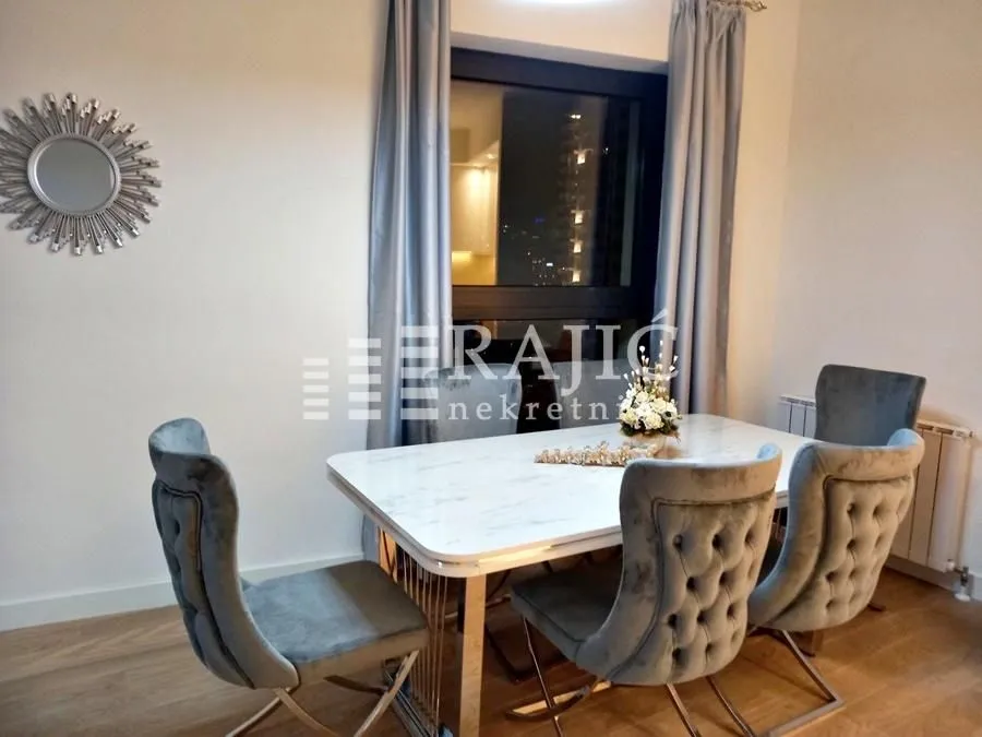 Dining area with a table, chairs, and a decorative wall mirror.