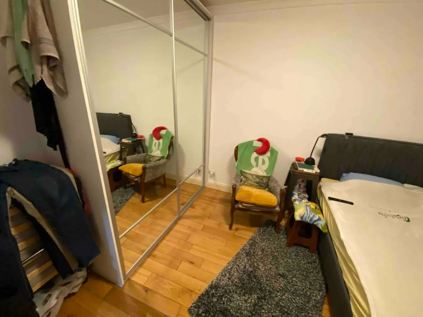 Manja spavaća soba sa krevetom, velikim plakarom sa ogledalom i foteljom.