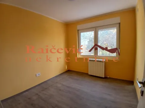 Prazna soba sa žutim zidovima, prozorom i laminatom na podu. - image 2