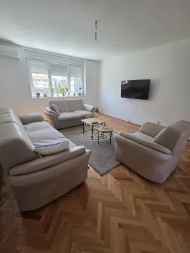 Dnevna soba sa garniturom za sedenje, stočićima i televizorom na zidu. - image 2
