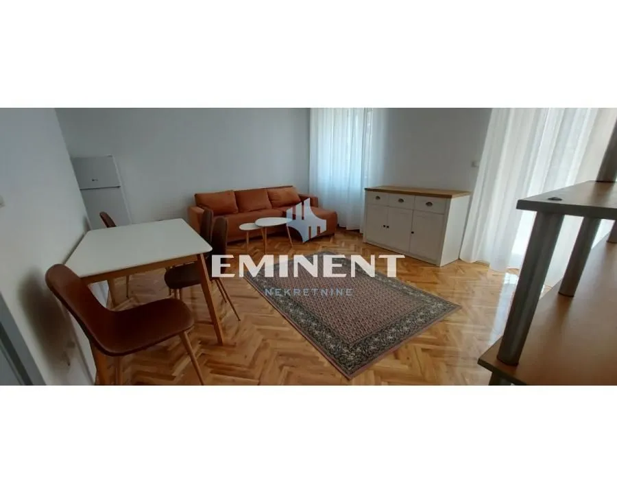 Dnevni boravak sa garniturom, trpezarijskim stolom i parketom na podu.