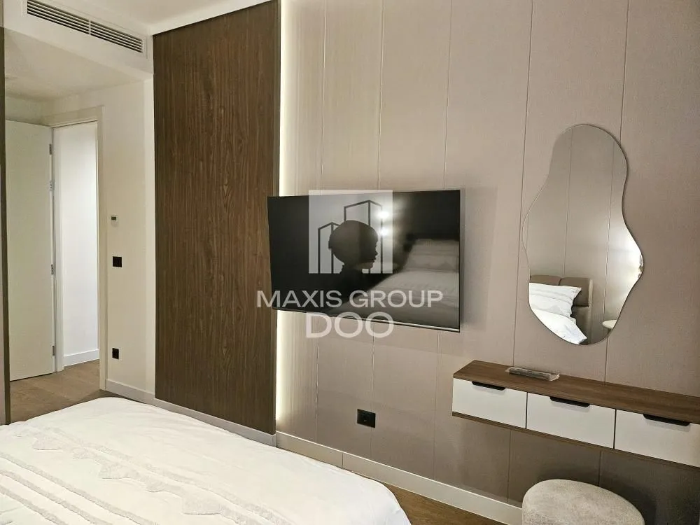 Modern bedroom with a double bed, TV, and a wall mirror.