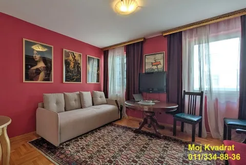 Dnevna soba sa kaučem, okruglim stočićem, slikama na zidu i prozorom. - image 2