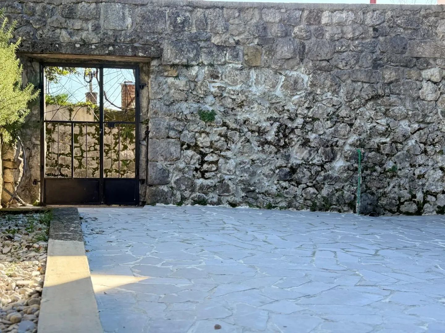 Dvorište sa kamenim zidom i popločanim podom.
