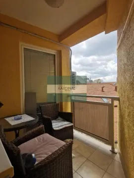 Natkriveni balkon sa garniturom za sedenje i pogledom na okolne krovove. - image 23