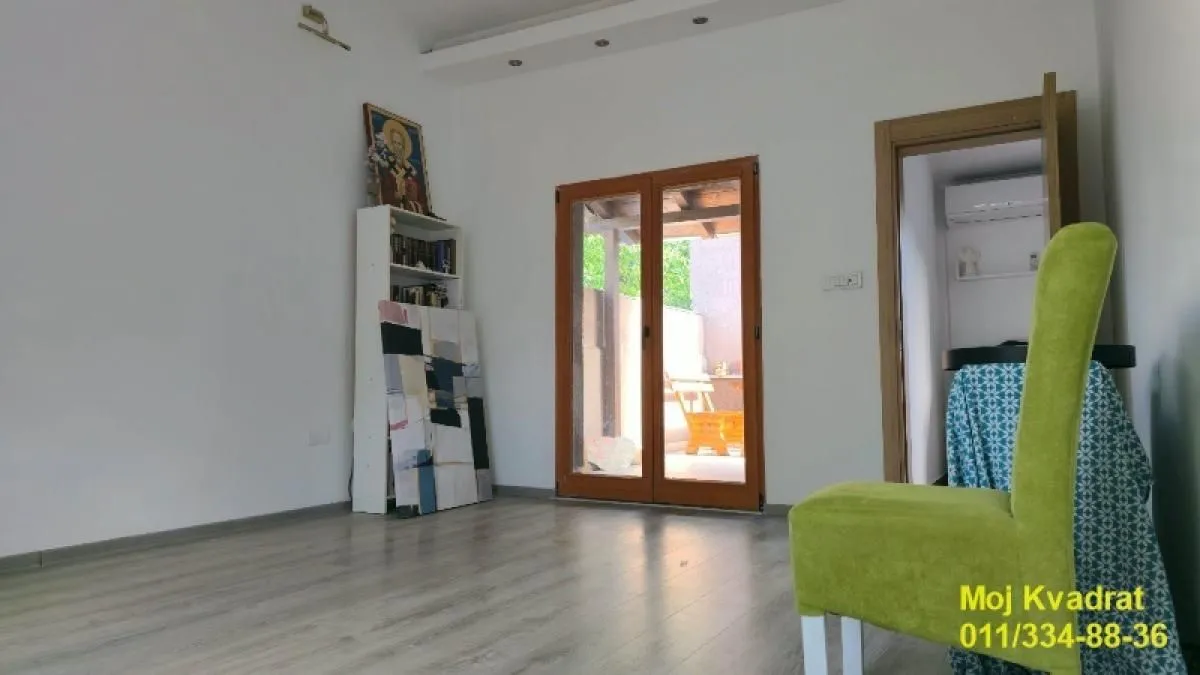 Dnevna soba sa laminatom i izlazom na terasu.