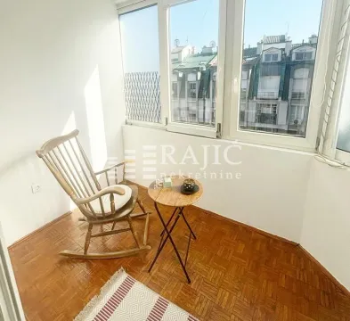Enclosed balcony with a rocking chair and a small table. - image 8