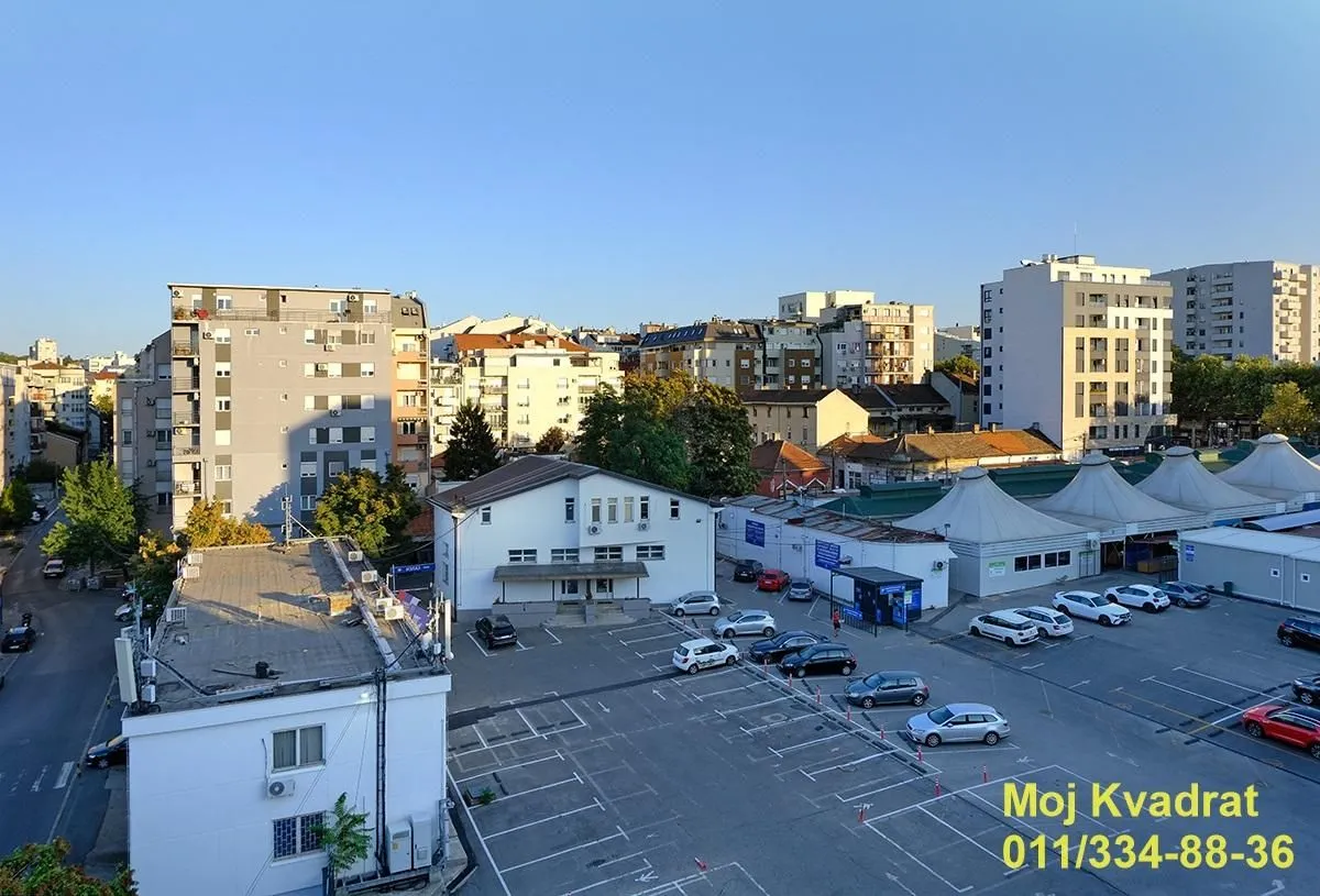 Pogled sa prozora na okolne zgrade i parking.